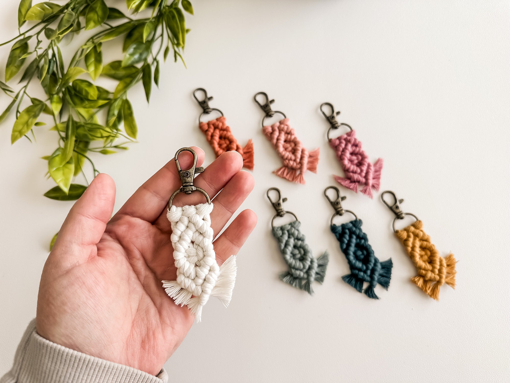 Mini macrame keychain held in a hand for size comparison. 